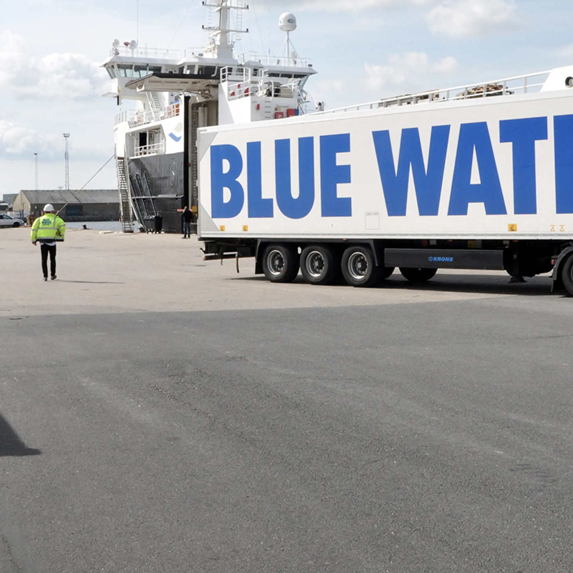 Man walking next to a Blue Water Shipping truck at the Harbour of Singapore